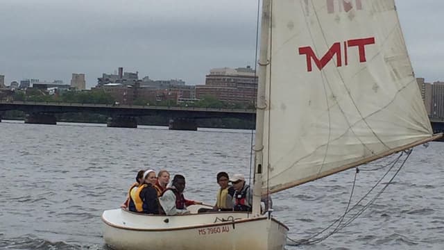 Seven students, from Fitchburg High School and MIT, sailing an MIT sailboat on the Charles River.